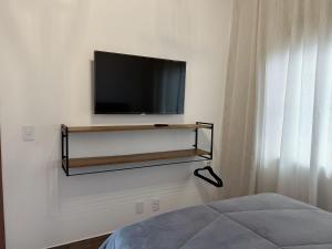 a flat screen tv on a wall with a shelf at chalé cantin casa temporada 900 m praça tiradentes in Tiradentes