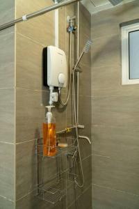 a shower in a bathroom with a soap dispenser on the wall at Miro Resthouse by the Pool in Kajang