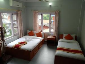zwei Betten in einem Zimmer mit zwei Fenstern in der Unterkunft Hotel Blue moon Pokhara in Pokhara