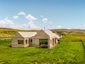 a house on a hill with a green yard at The Two Byres in Trumpan