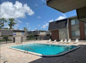 einen Pool mit Stühlen und ein Gebäude in der Unterkunft ConCrete Suite 5 Min Walk to Shands UF in Gainesville