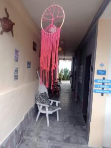 Zimmer mit einem Stuhl und einem roten Vorhang in der Unterkunft Guest House do Magoo in Arraial do Cabo