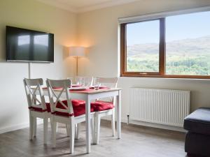 een eetkamer met een tafel met stoelen en een televisie bij Rivendell Cottage in Fort Augustus