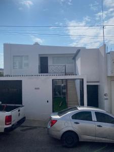 ein weißes Haus mit einem davor geparkt in der Unterkunft Bonito y Cómodo Departamento in Zacatecas