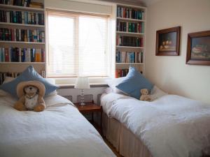 two stuffed teddy bears sitting on two beds in a bedroom at Harbour View in Pevensey