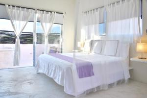 a white bedroom with a bed and a large window at Villas Geminis Boutique Condohotel in Tulum
