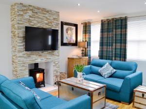 a living room with blue couches and a fireplace at Key To The Esk in Longtown