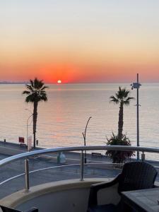 a boat in the water with palm trees and a sunset at Luxury apartment with sea view in Mezitli