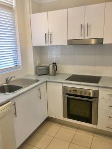 a kitchen with white cabinets and a sink and a stove at Kiama beachside apartment in Kiama +5 photos