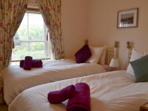 two beds with stuffed animals on them in a bedroom at Oswin Cottge in Alnwick