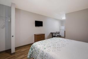 1 dormitorio con 1 cama y TV en la pared en HomeTowne Studios by Red Roof Covington, GA en Covington