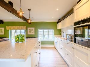 a kitchen with white cabinets and green walls at The Apple Store - Uk32623 in Swannington