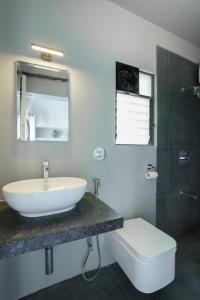 a bathroom with a sink and a toilet and a mirror at Grey Stone - Lakefront PentHouse Family Rooms in Kolhapur