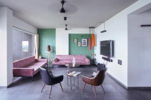 a living room with pink furniture and a tv at Grey Stone - Lakefront PentHouse Family Rooms in Kolhapur