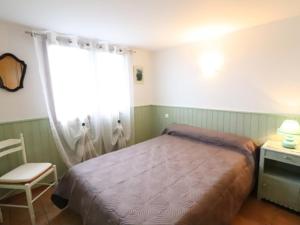 ein Schlafzimmer mit einem Bett, einem Stuhl und einem Fenster in der Unterkunft Gîte Vitrac, 3 pièces, 4 personnes - FR-1-742-450 in Vitrac