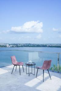 duas cadeiras e uma mesa num pátio com água em Grey Stone - Lakefront PentHouse Family Rooms em Kolhapur