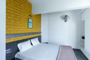 a bedroom with a bed with a yellow brick wall at Grey Stone - Lakefront PentHouse Family Rooms in Kolhapur