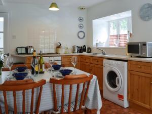 a kitchen with a table and a washing machine at Shore Cottage - Uk12524 in Garlieston