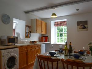 uma cozinha com uma mesa com cadeiras e um micro-ondas em Shore Cottage - Uk12524 em Garlieston