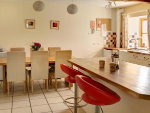a kitchen with a wooden table and red chairs at Leonard Barn in Stonehouse