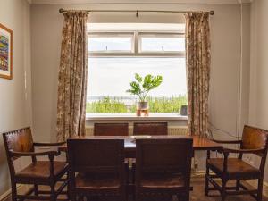 jadalnia ze stołem i krzesłami oraz oknem w obiekcie Ocean View Cottage w mieście Burry Port