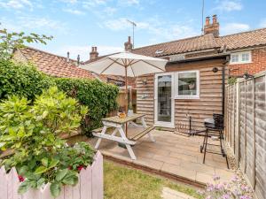 a patio with a table and an umbrella at Heartwarming Cottage in Wickham Market