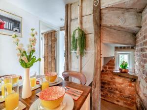 ein Esszimmer mit einem Holztisch und einer Ziegelwand in der Unterkunft Heartwarming Cottage in Wickham Market