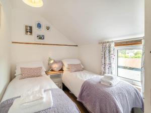 two beds in a small room with a window at Heartwarming Cottage in Wickham Market