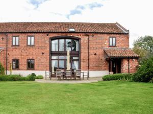 a brick house with tables and chairs in a yard at Woodpecker Barn - Cwl in Sculthorpe