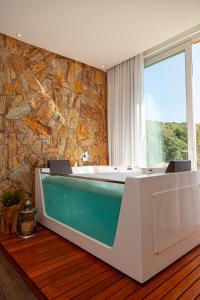 a bath tub in a room with a stone wall at Villa Toscana - Vale dos Vinhedos in Bento Gonçalves