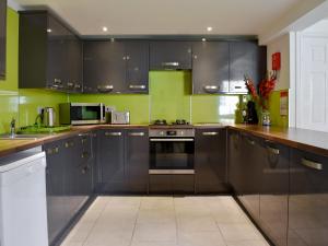 a kitchen with stainless steel appliances and black cabinets at St Hildas Rest in Hinderwell