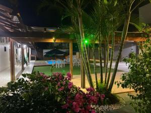 a courtyard with palm trees and flowers at night at Casa de praia Le Frute. Mar, piscina, descanso! in Vila Velha