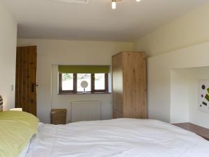 1 dormitorio con cama blanca y ventana en The Old Dairy en Thorncombe