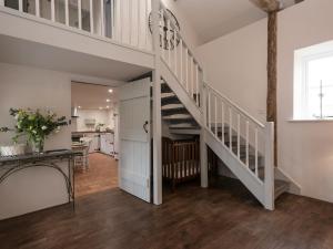 a white staircase in a living room with a kitchen at Heron Barn in Little Hautbois