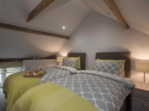 ein Schlafzimmer mit einem großen Bett mit gelber und grauer Decke in der Unterkunft Heron Barn in Little Hautbois