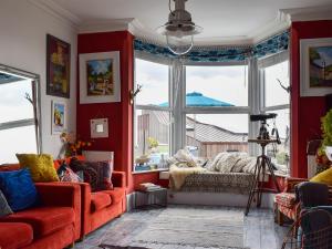 salon z czerwonymi ścianami, kanapą i oknami w obiekcie Fronks House w mieście Harwich