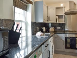 una cucina con armadi bianchi e piano di lavoro nero di Doddick Three - Uk33383 a Threlkeld
