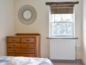 una camera da letto con cassettiera, specchio e finestra di Doddick Three - Uk33383 a Threlkeld