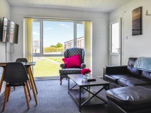 ein Wohnzimmer mit einem Sofa, einem Stuhl und einem Fenster in der Unterkunft 10 Castaway-uk45095 in Kessingland