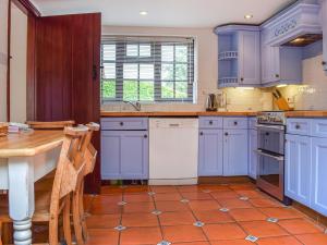 a kitchen with blue cabinets and a wooden table at Honeysuckle Cottage in Mickleton