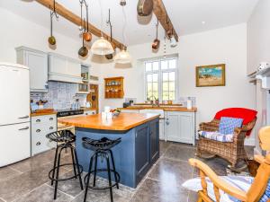 a kitchen with white cabinets and a blue island at The Farmhouse - Uk33419 in West Witton