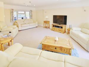 sala de estar con muebles blancos y TV de pantalla plana en Irenic Lodge, en Netley