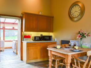 a kitchen with a table and a clock on the wall at Garden Cottage in Coldingham