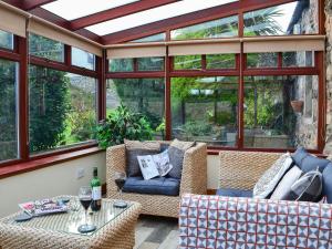 a screened in porch with a couch and a table at Garden Cottage in Coldingham