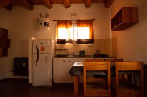 cocina con nevera, mesa y sillas en Cabaña La Yumba en Capilla del Monte
