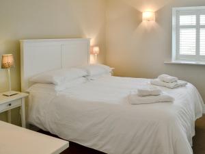 a bedroom with a white bed with towels on it at The Maltings in Bamburgh