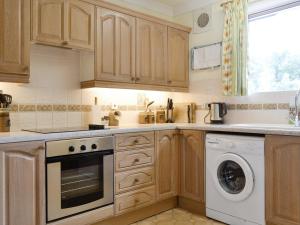a kitchen with wooden cabinets and a washer and dryer at Lairds Cast in Banchory