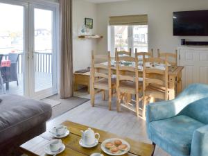 a living room with a table and a dining room at Davids Island in Wroxham