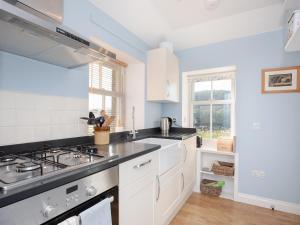 a kitchen with white cabinets and a stove top oven at Nettlebush Cottage-uk5629 in Drummelzier