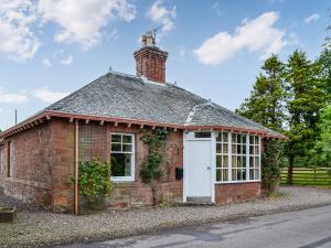 a brick building with a white door and a chimney at South Lodge in Forgandenny